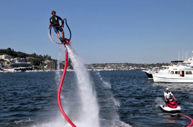 hombre haciendo flyboard con un pueblo de fondo